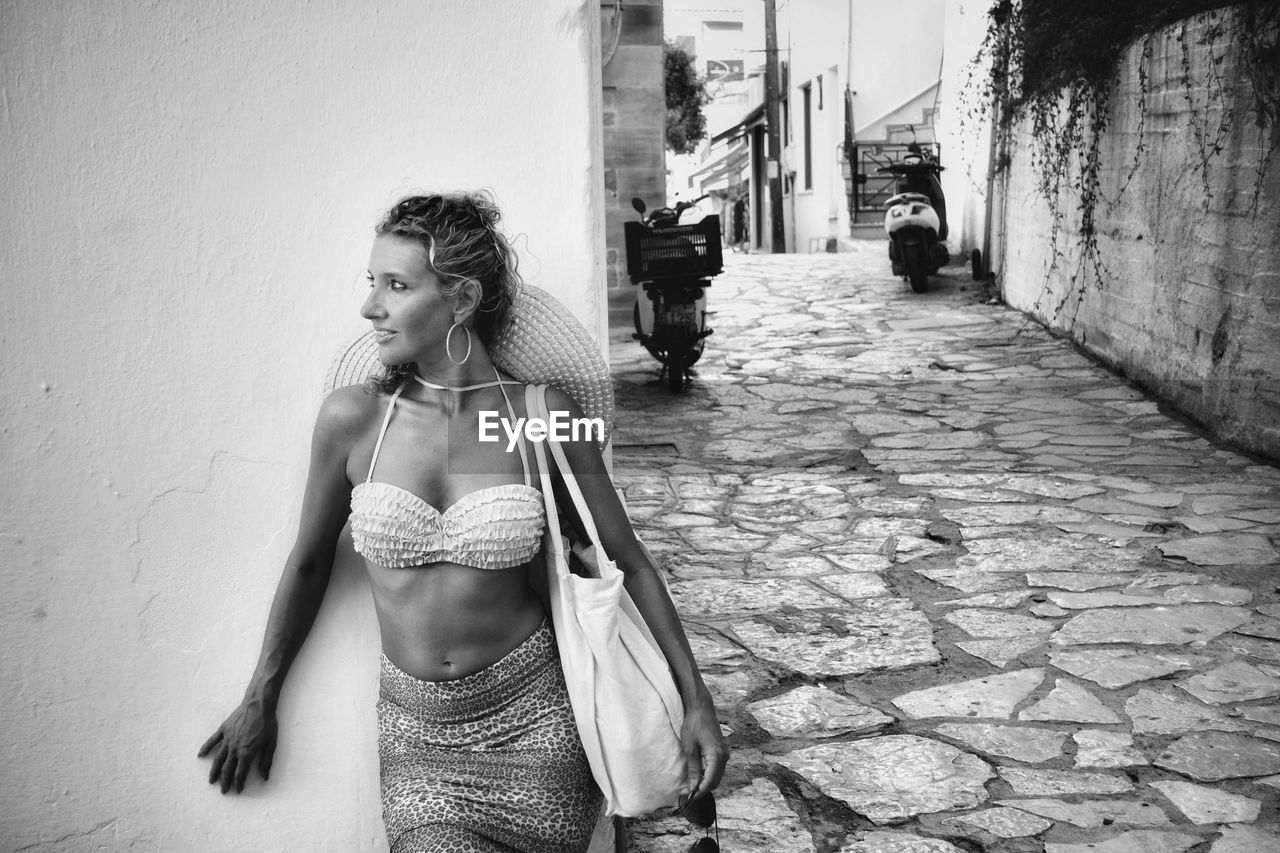 A girl in a summer accessory next to the wall in black and white technique