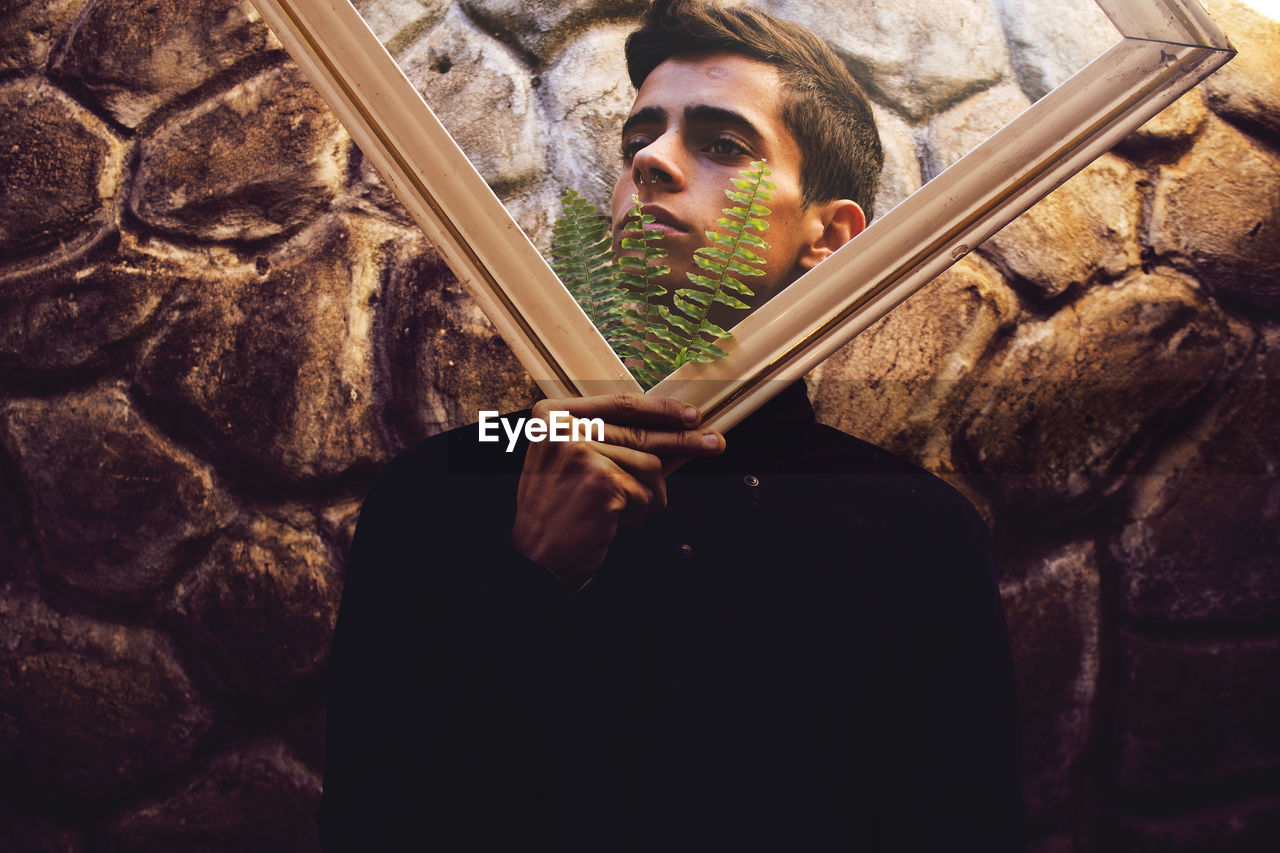 Portrait of young man holding picture frame