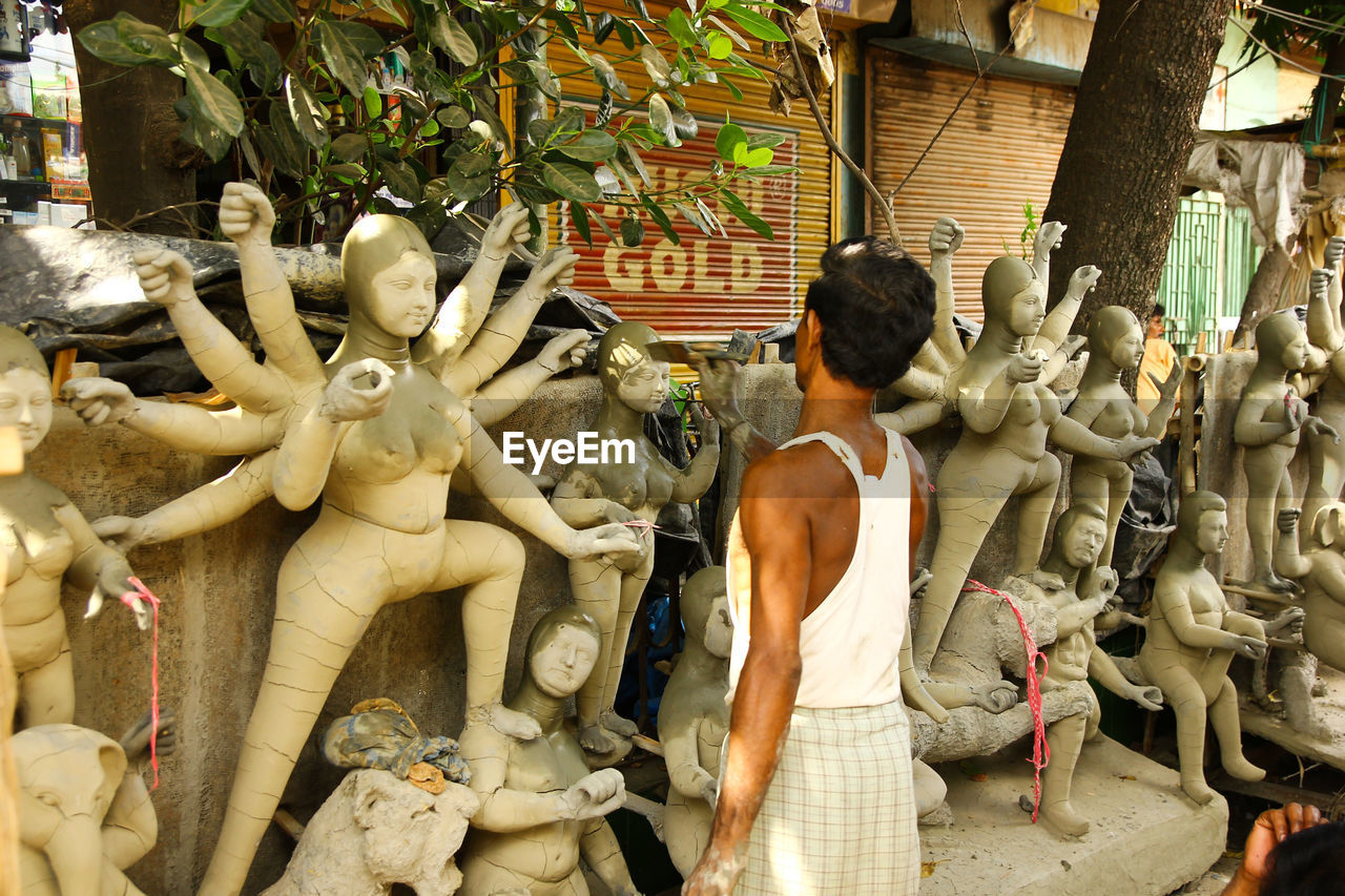 REAR VIEW OF MAN STATUES AT TEMPLE