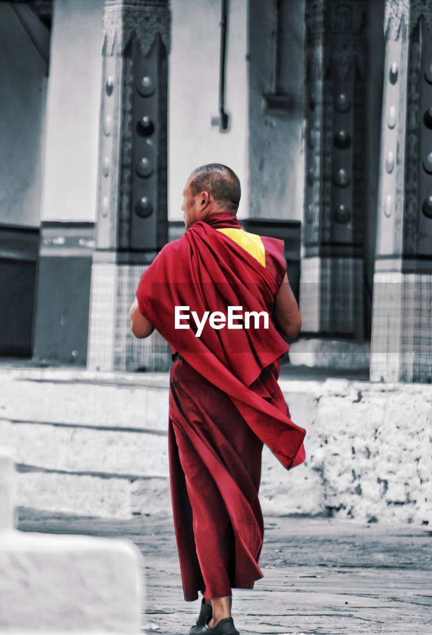 REAR VIEW OF MAN WALKING IN TEMPLE