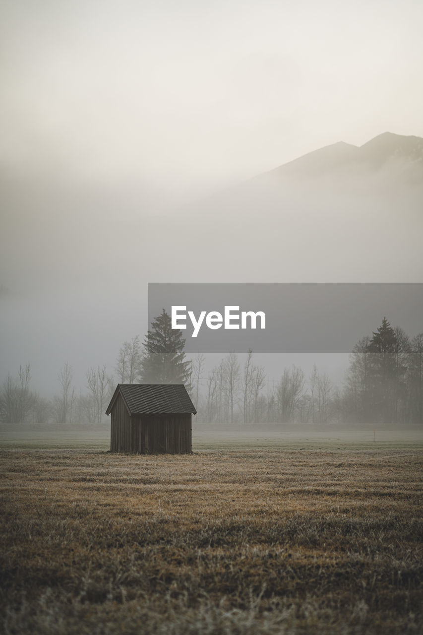 BARN ON FIELD AGAINST SKY