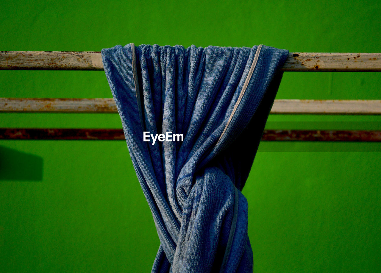 Close-up of blue towel against green wall