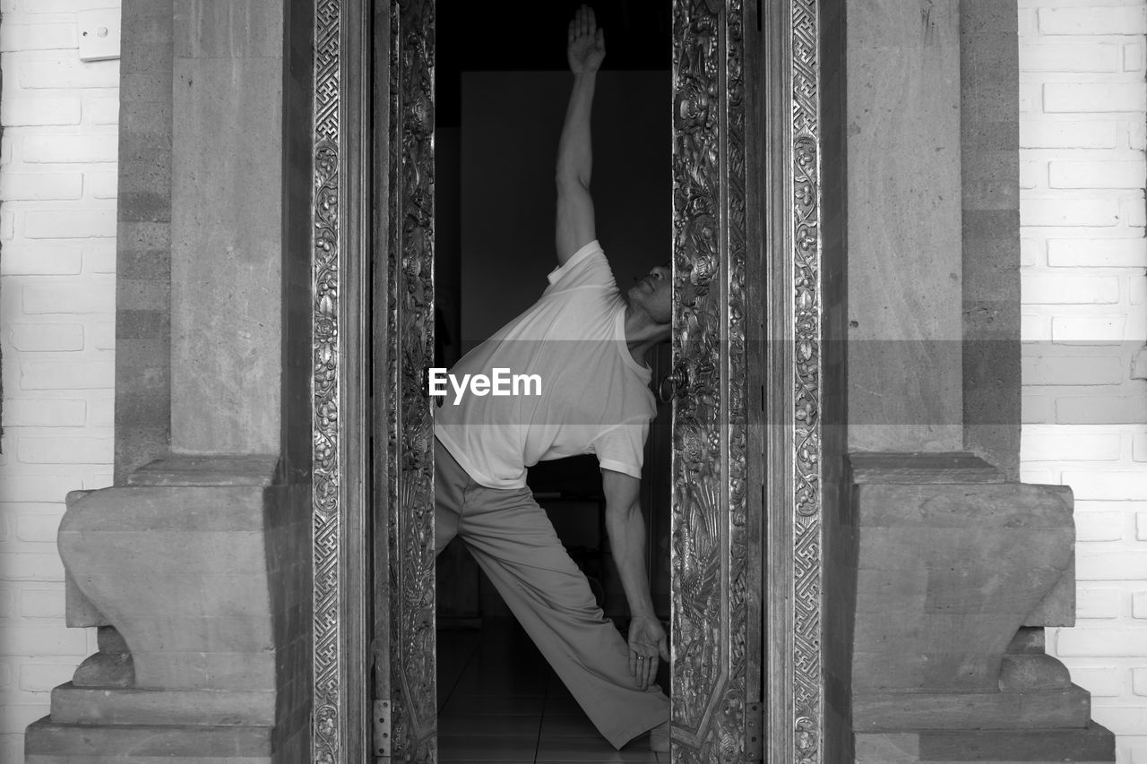 Man doing yoga seen through doorway
