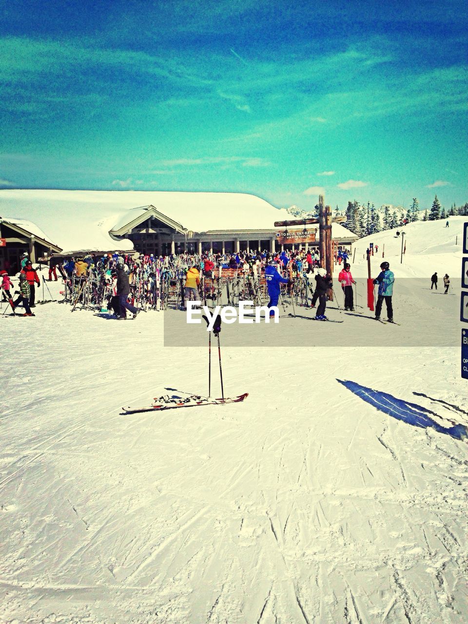 People on snow covered field against sky during sunny day