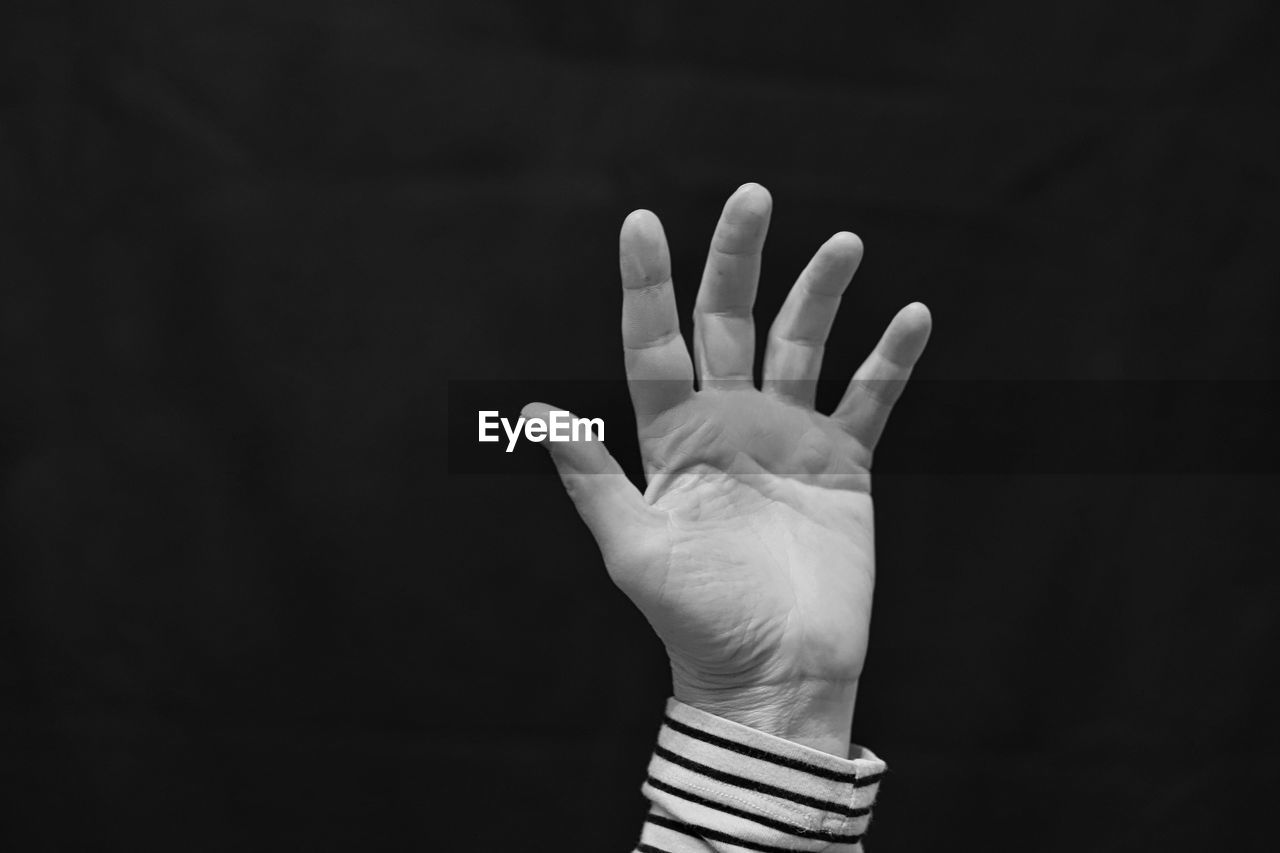 Cropped image of person hand against black background
