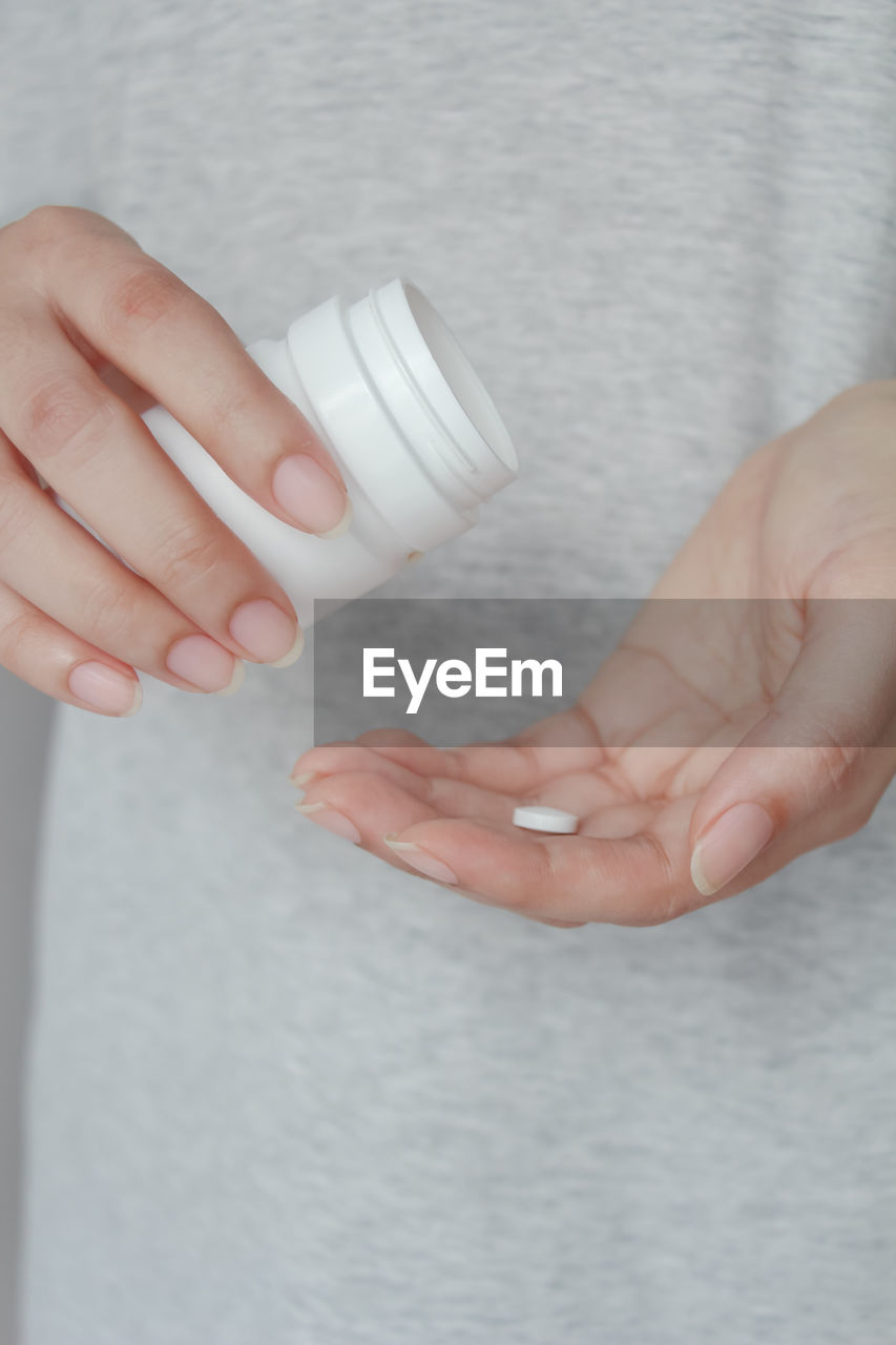 Close up of female hands pouring medicine tablets from bottle into her hand