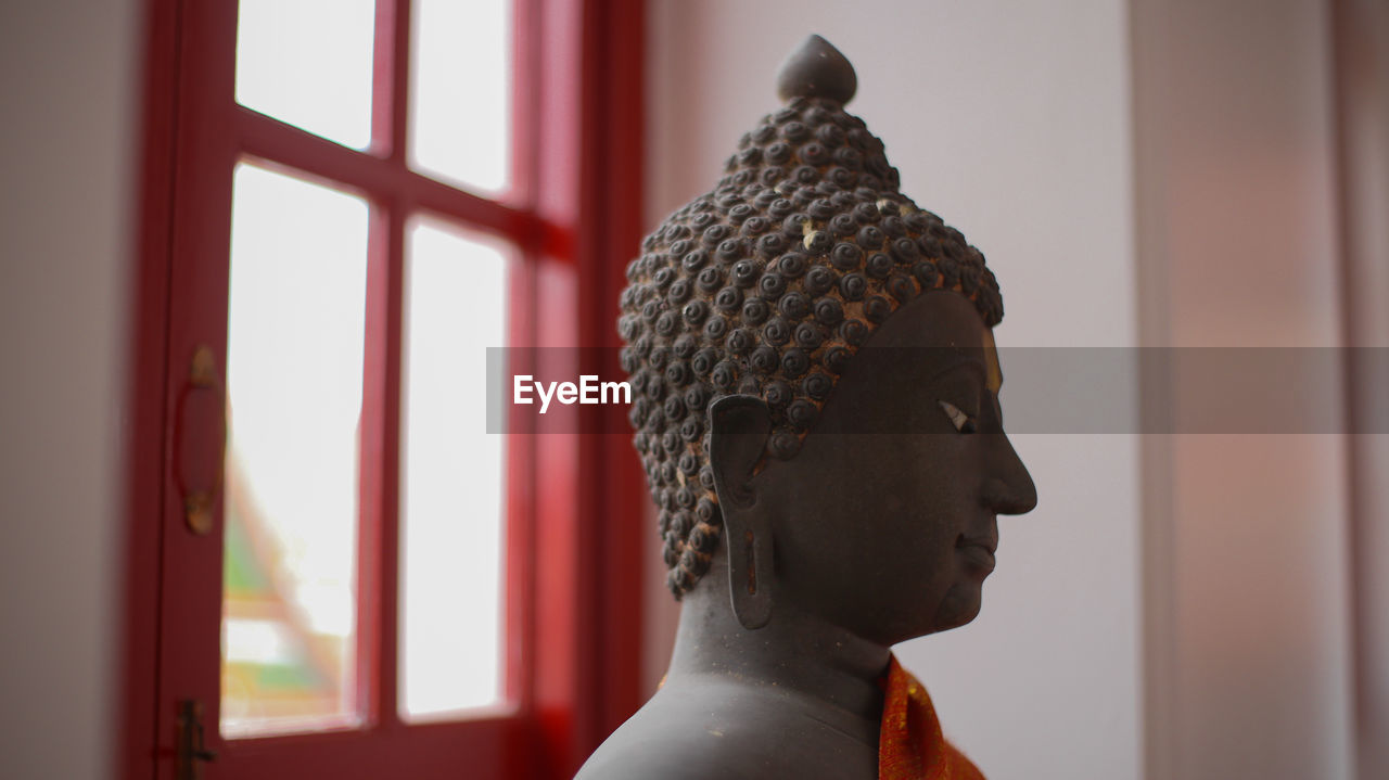 CLOSE-UP OF A STATUE AGAINST THE WINDOW