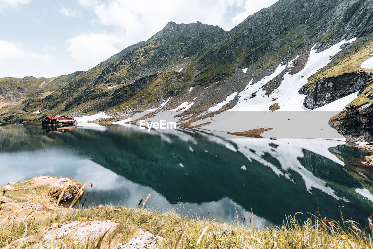 Snow patches on mountain ridge  with lake and reflection