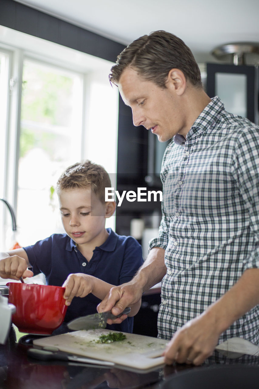 Father and son preparing food in kitchen