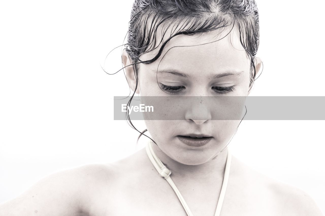 Close-up of girl looking down against white background
