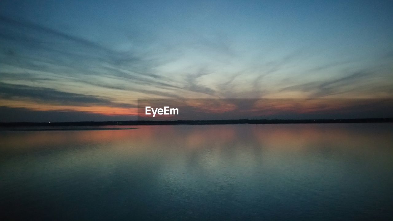 REFLECTION OF CLOUDS IN WATER AT SUNSET