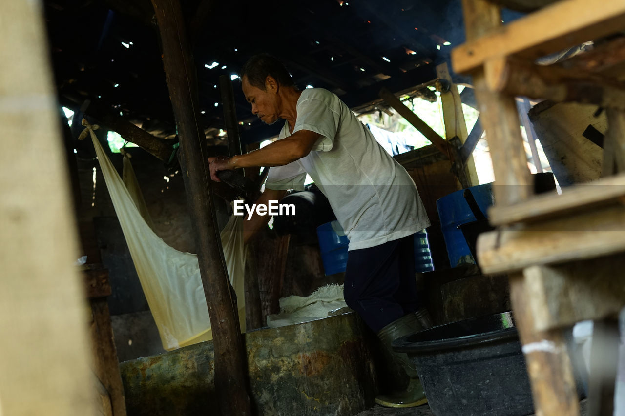 SIDE VIEW OF MAN WORKING ON WOODEN FLOOR