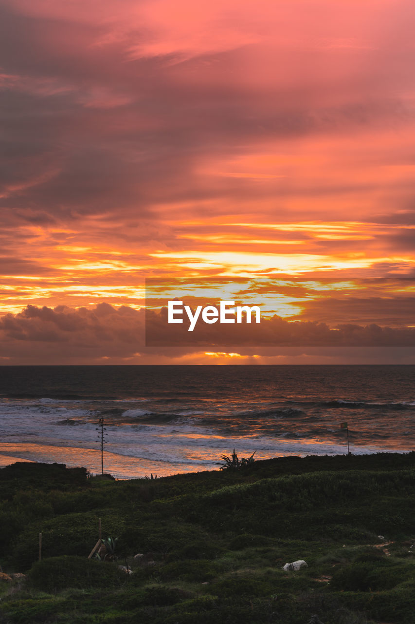 sky, sea, water, sunset, beauty in nature, cloud, beach, scenics - nature, land, nature, tranquility, horizon, tranquil scene, coast, ocean, horizon over water, orange color, environment, dramatic sky, afterglow, no people, landscape, idyllic, shore, outdoors, travel destinations, coastline, dawn, seascape, travel, sunlight, non-urban scene, tourism, sun, grass