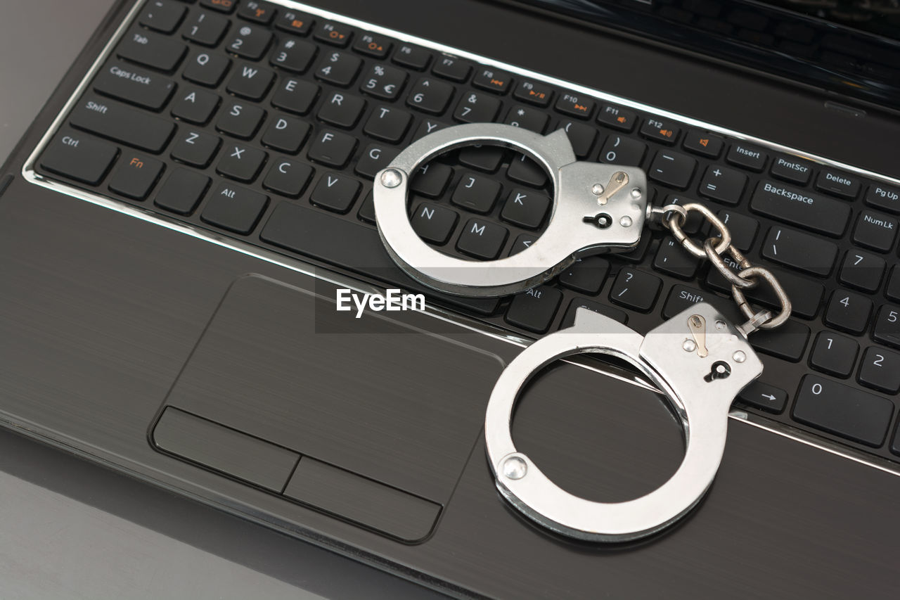 High angle view of handcuffs on laptop keyboard