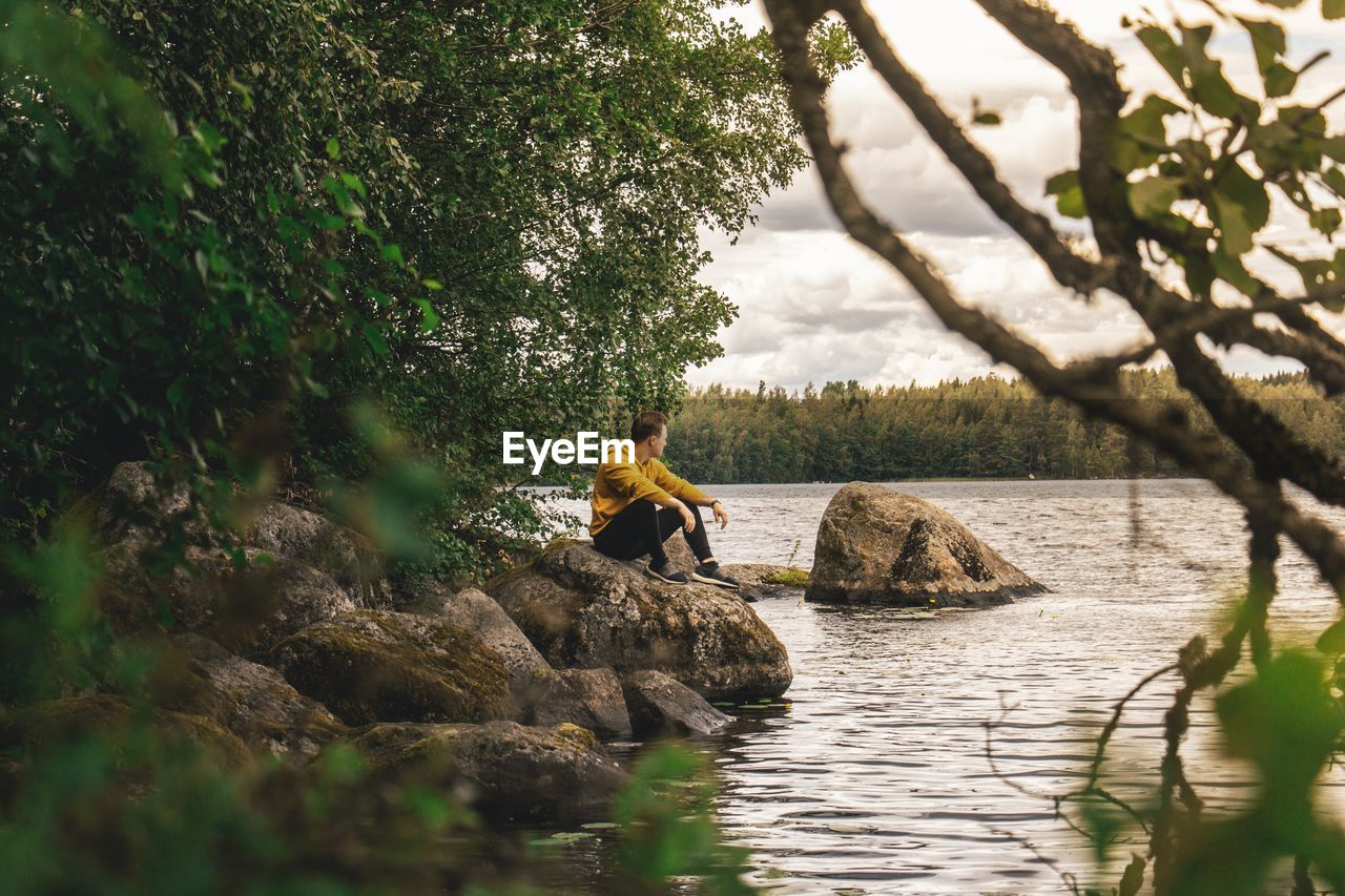 PEOPLE SITTING ON ROCK IN FOREST