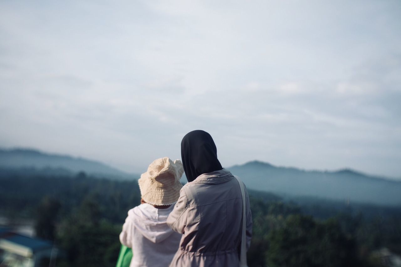 Rear view of friends looking at mountain against sky