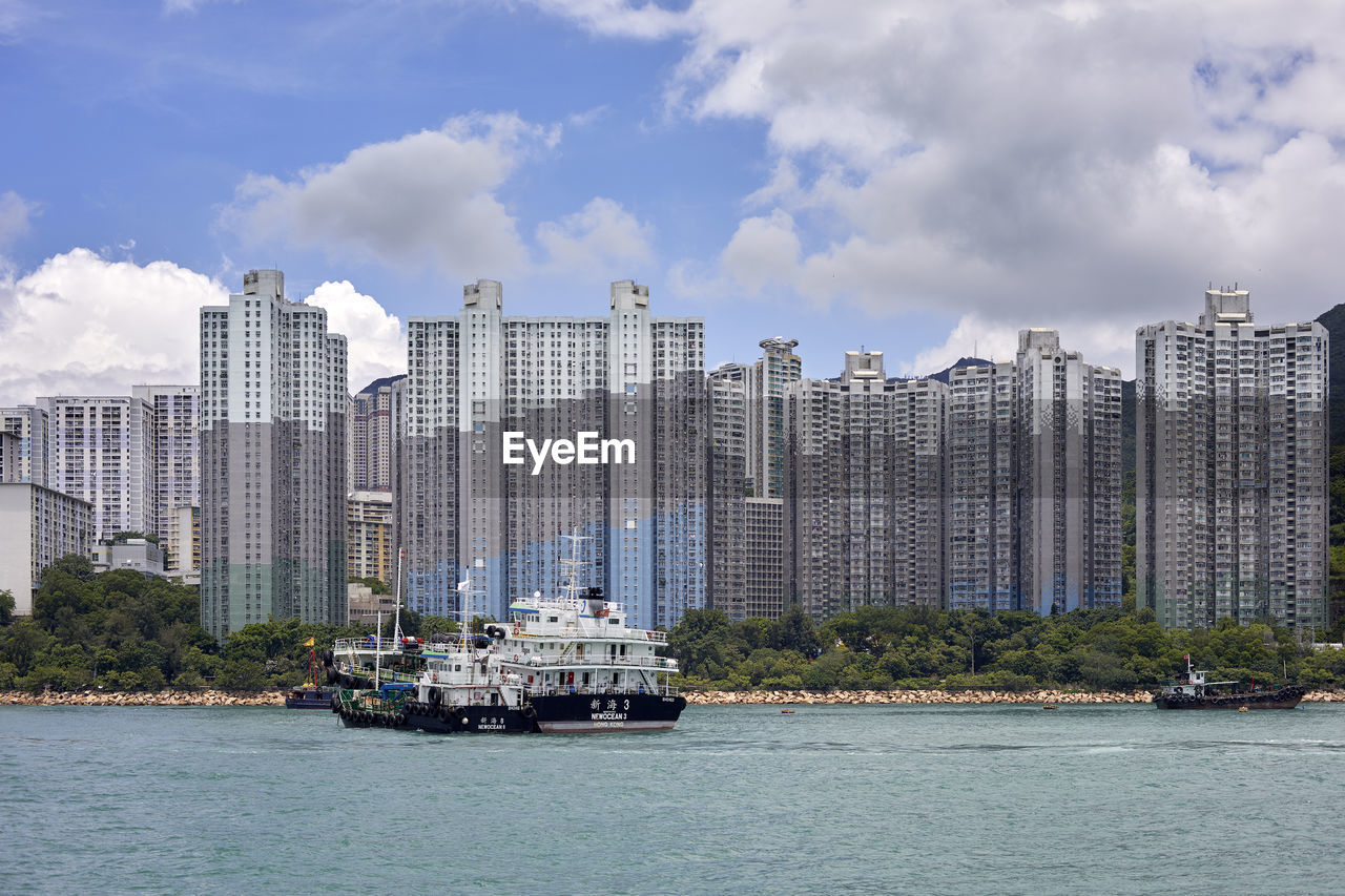 Sailboats in sea against modern buildings in city