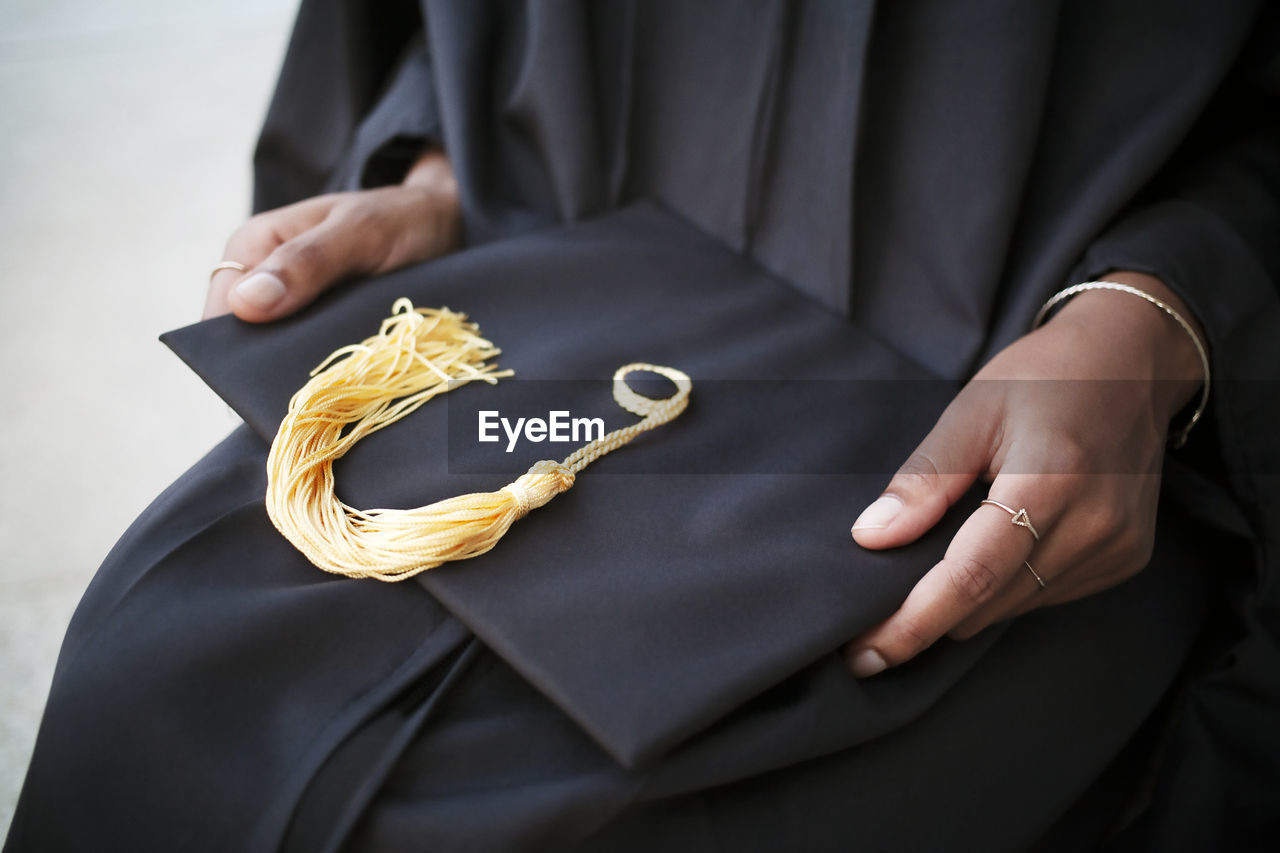 Mid-section of woman holding mortarboard