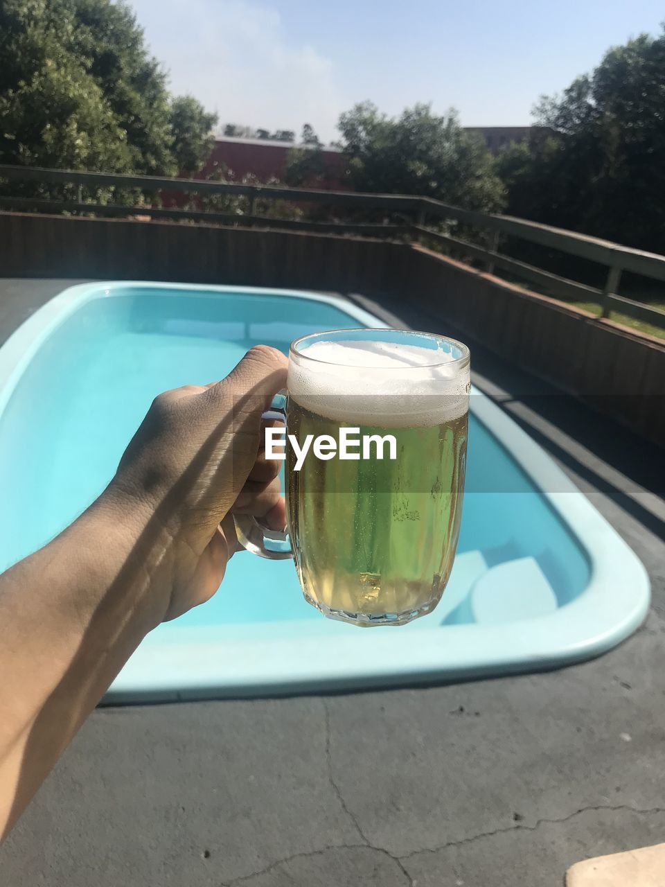 Midsection of person holding ice cream in swimming pool