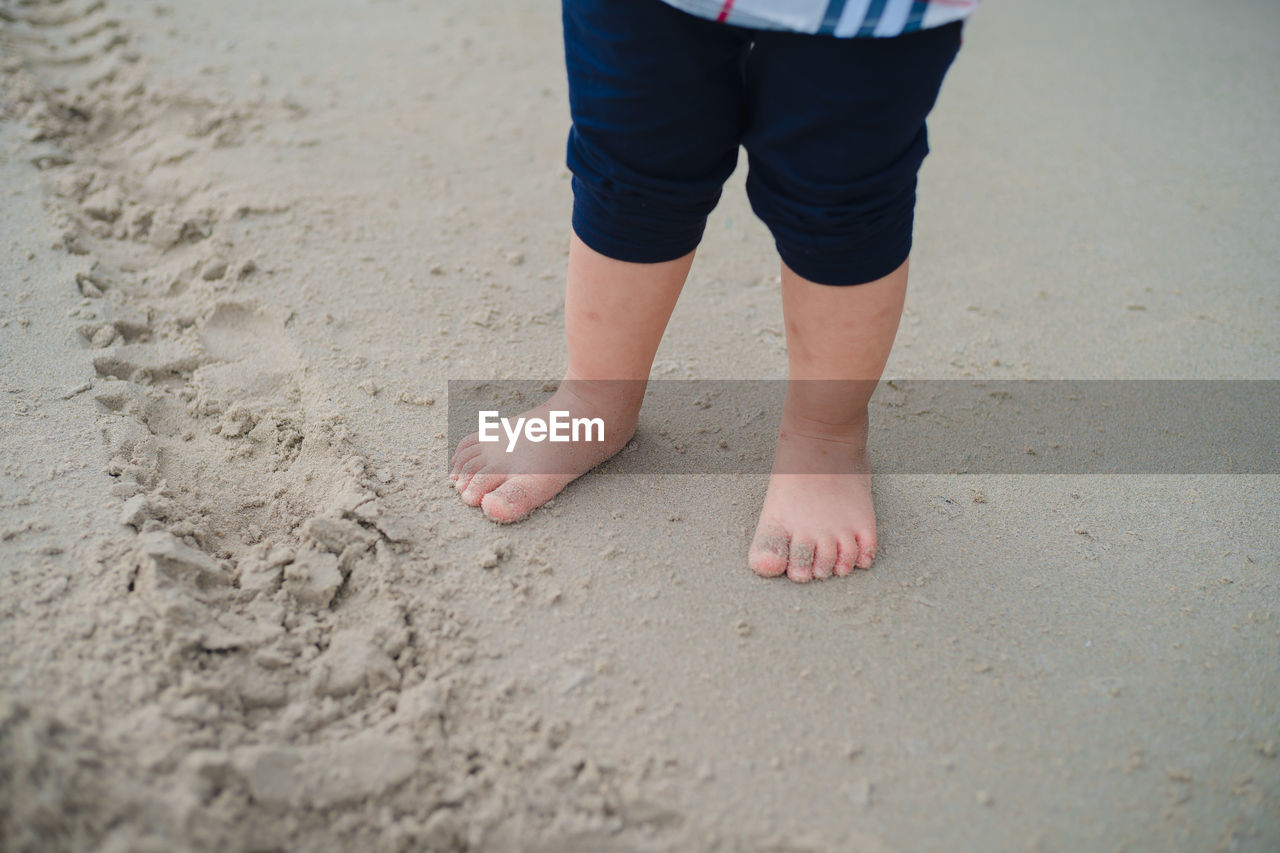 Low section of child standing on beach