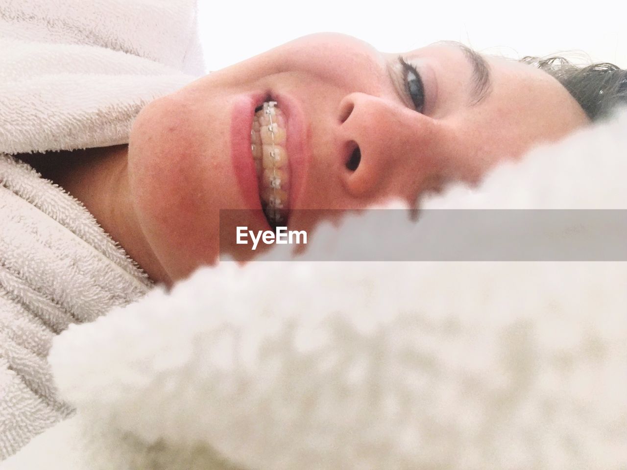 Close-up of woman with braces lying on bed at home