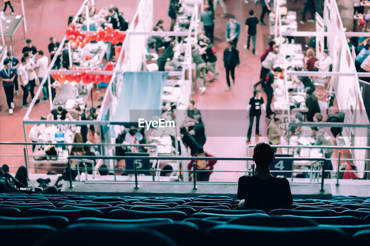 Woman sitting on bleachers looking at exhibition in stadium