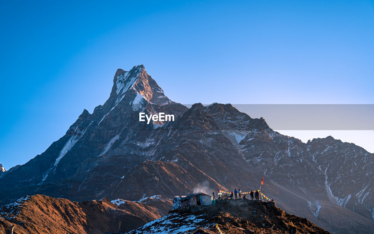 low angle view of rocky mountains against clear blue sky