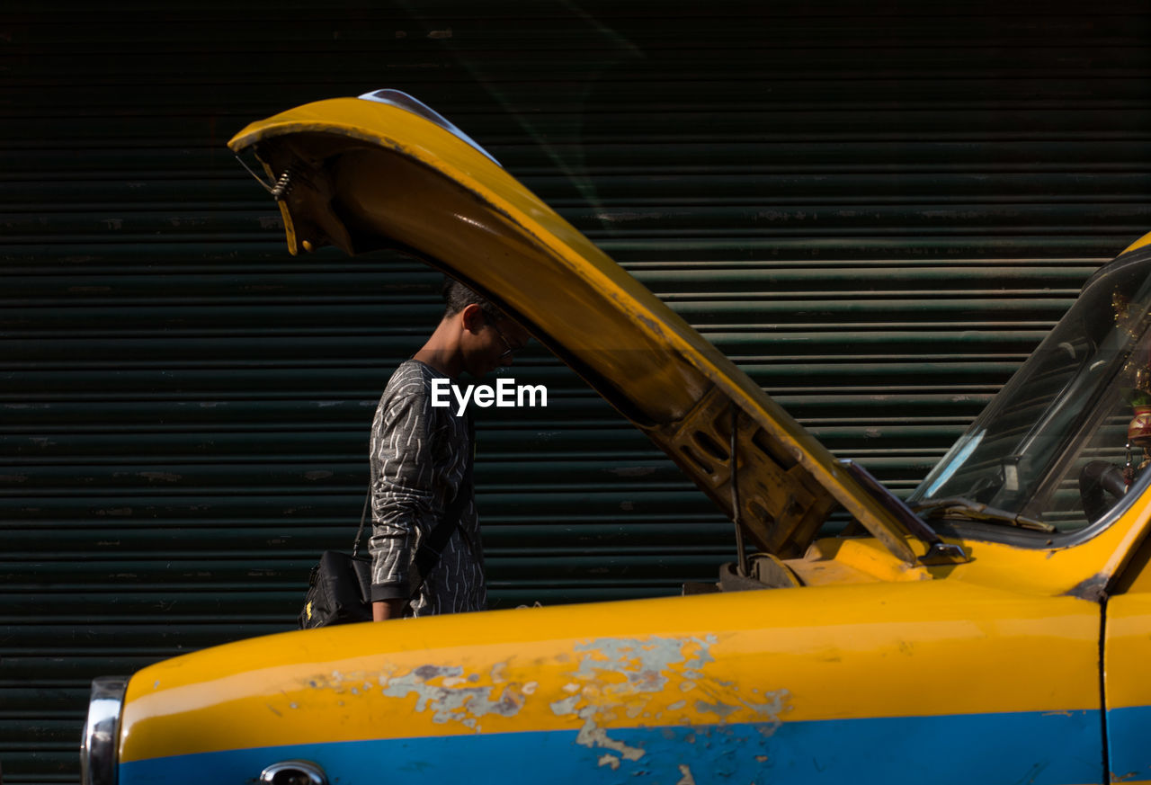 Side view of man standing by car