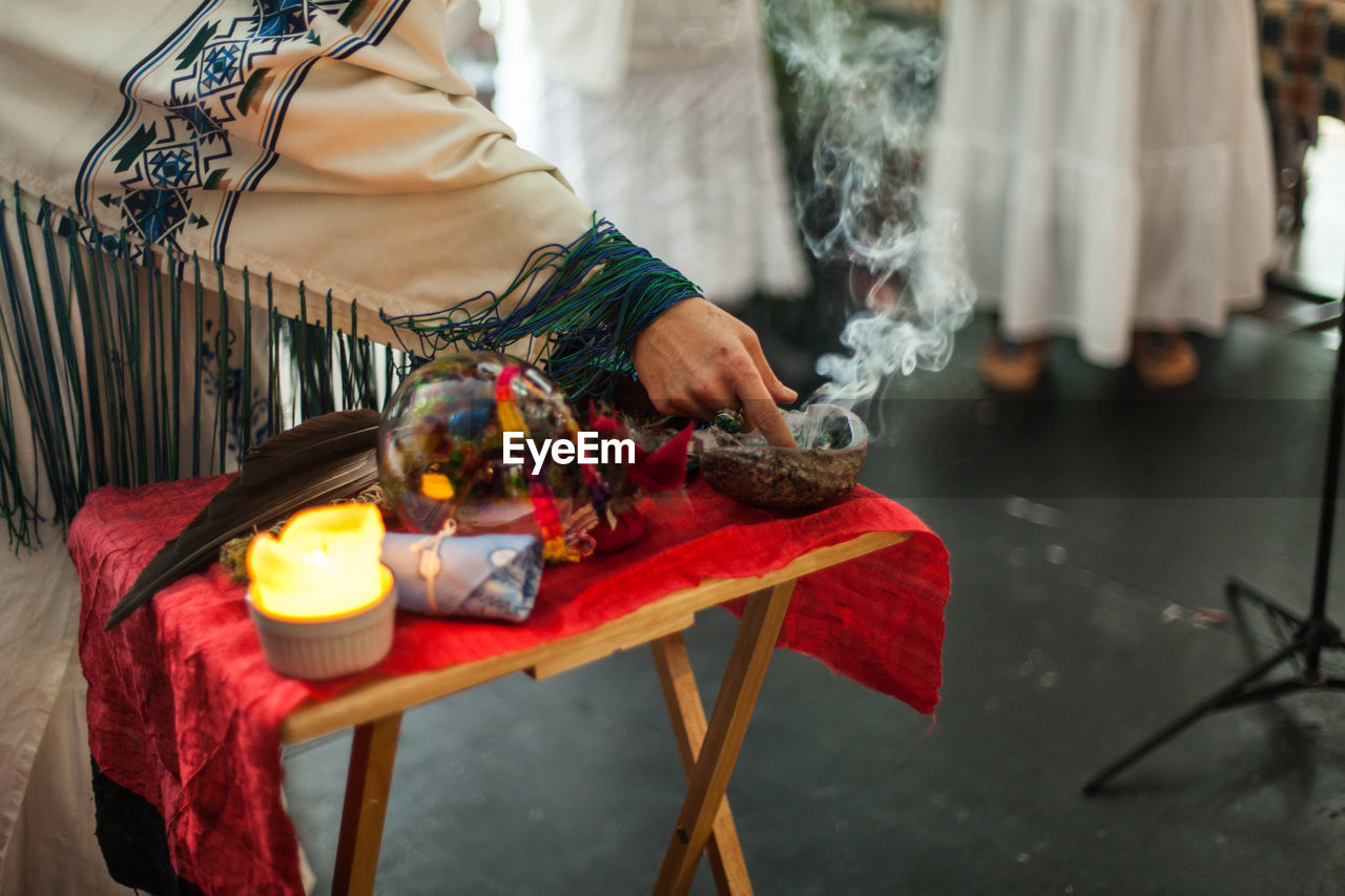 Midsection of man holding lit candles in temple