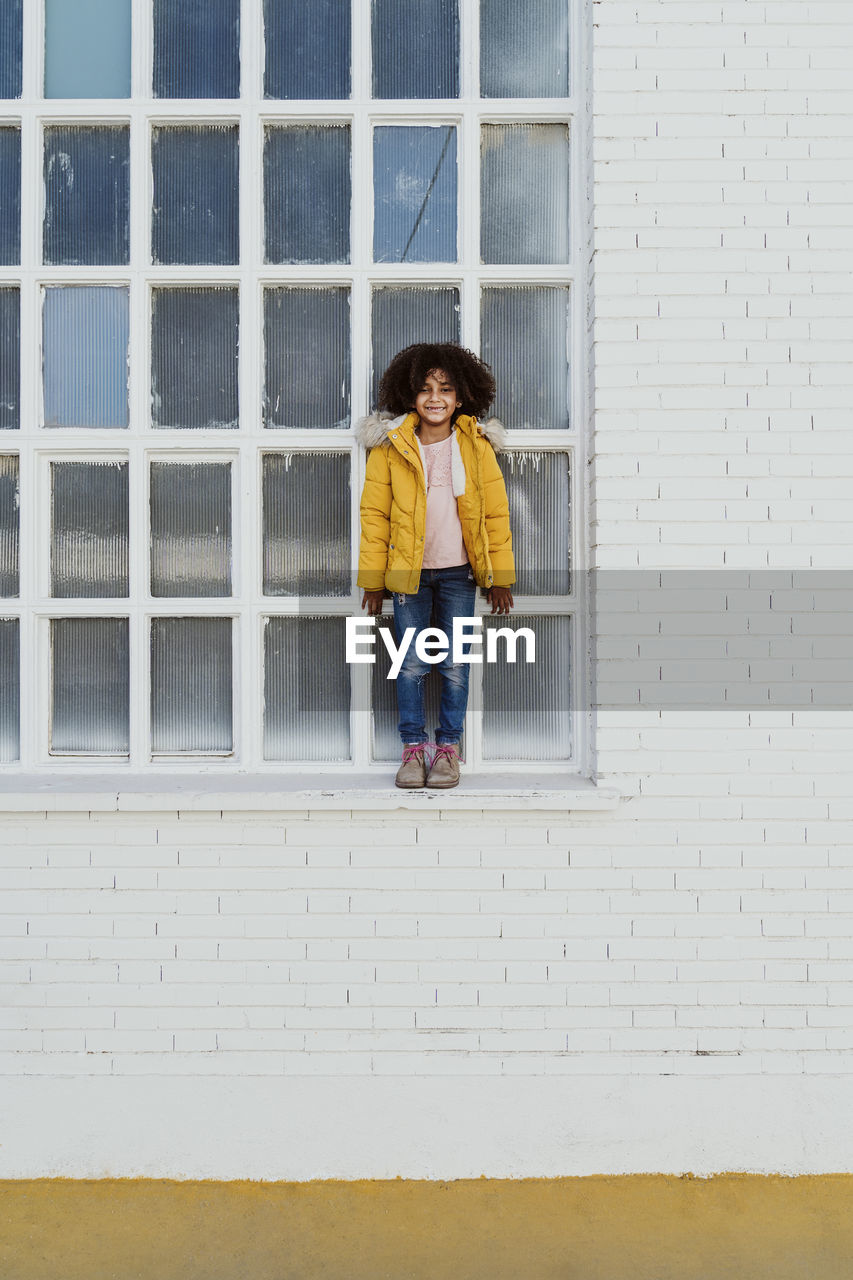 Portrait of girl standing on window sill