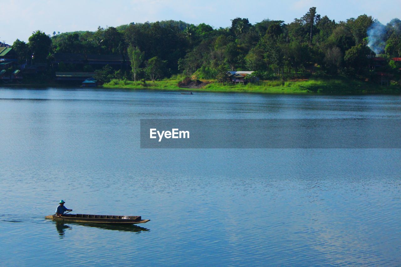 BOAT IN LAKE AGAINST TREES