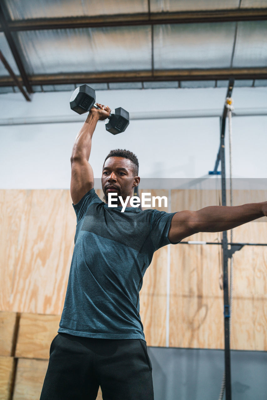 Man lifting dumbbell against wall