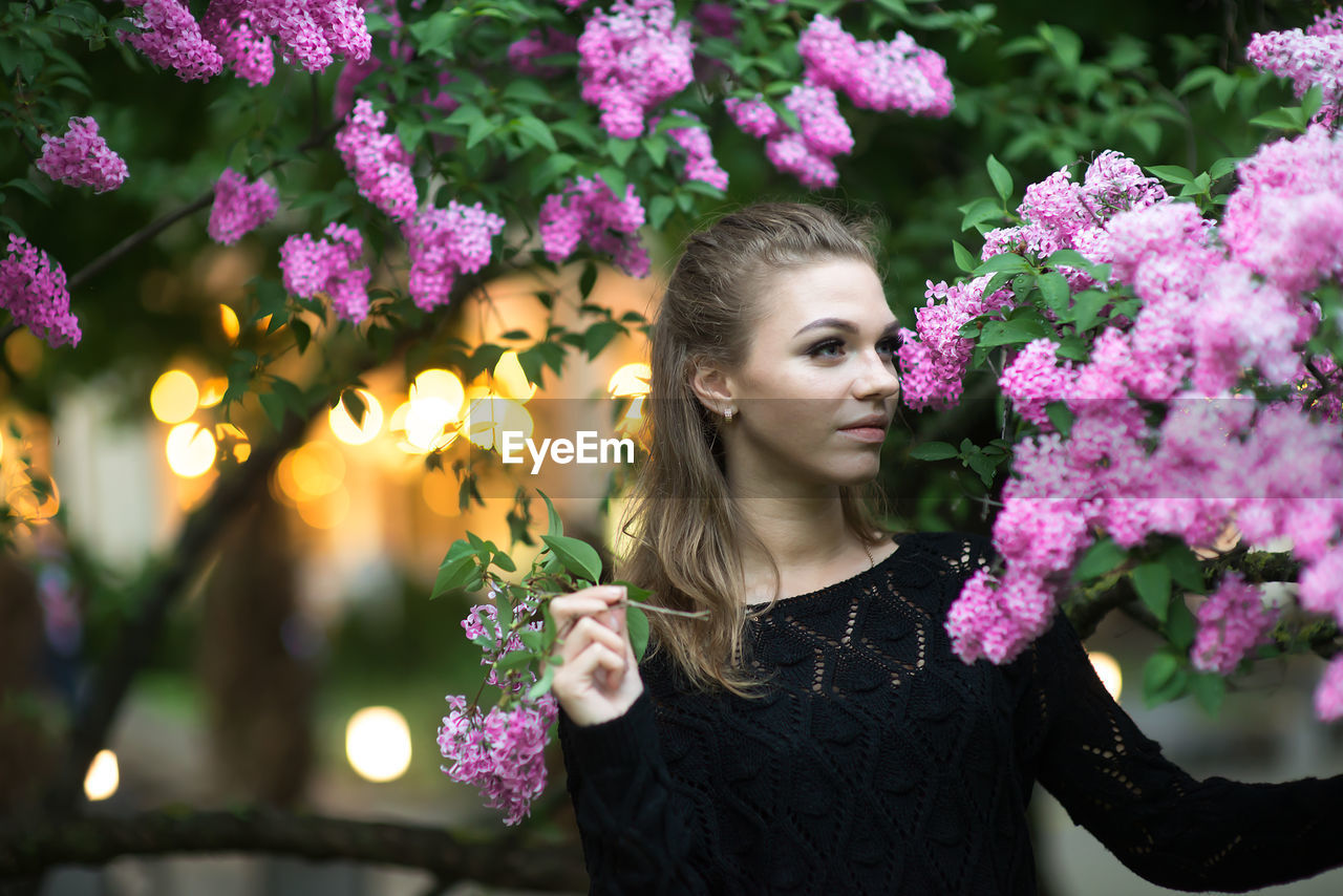 Young woman by purple flowers on branches