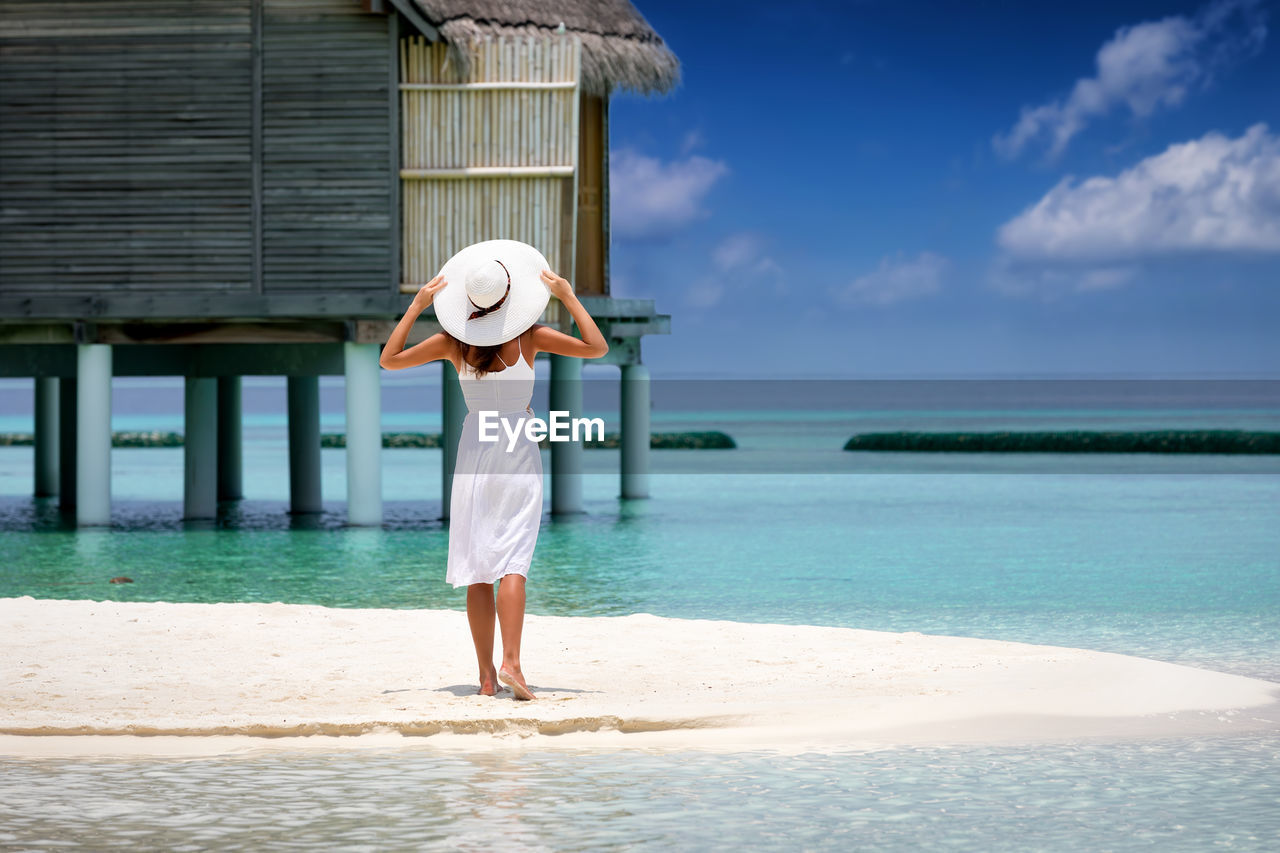 Rear view of woman standing at beach