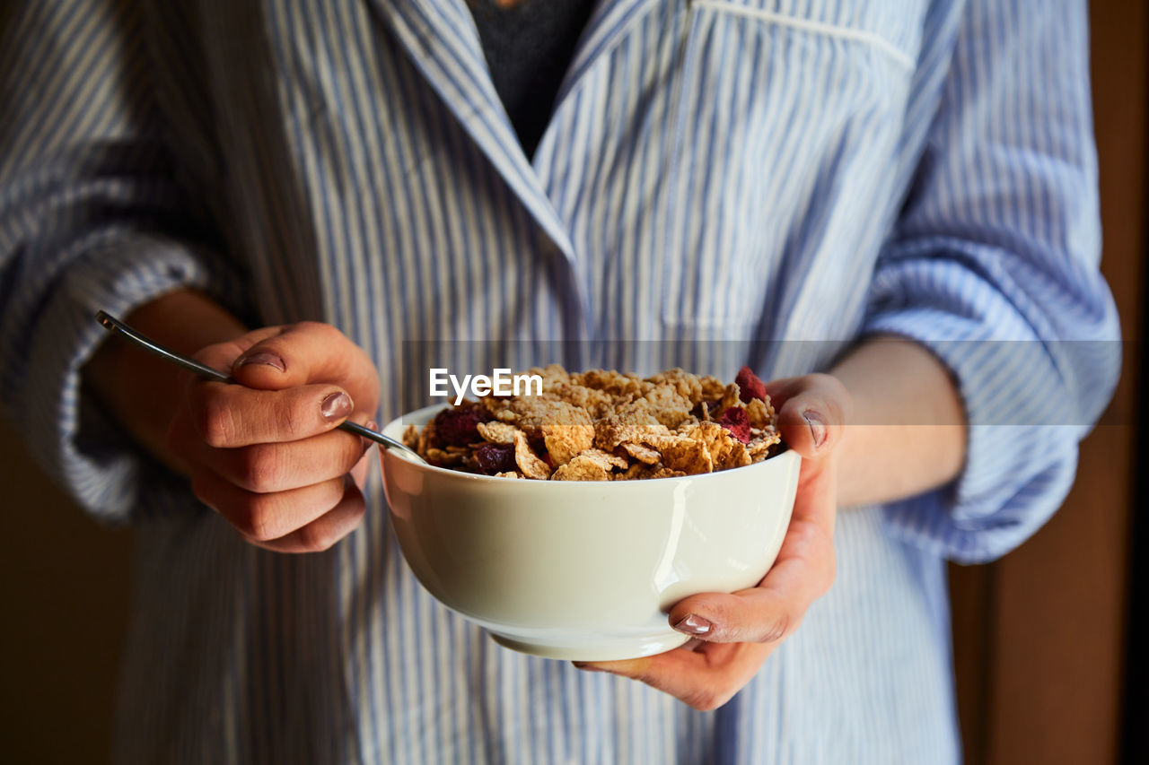 Young woman having breakfast next to a window at home