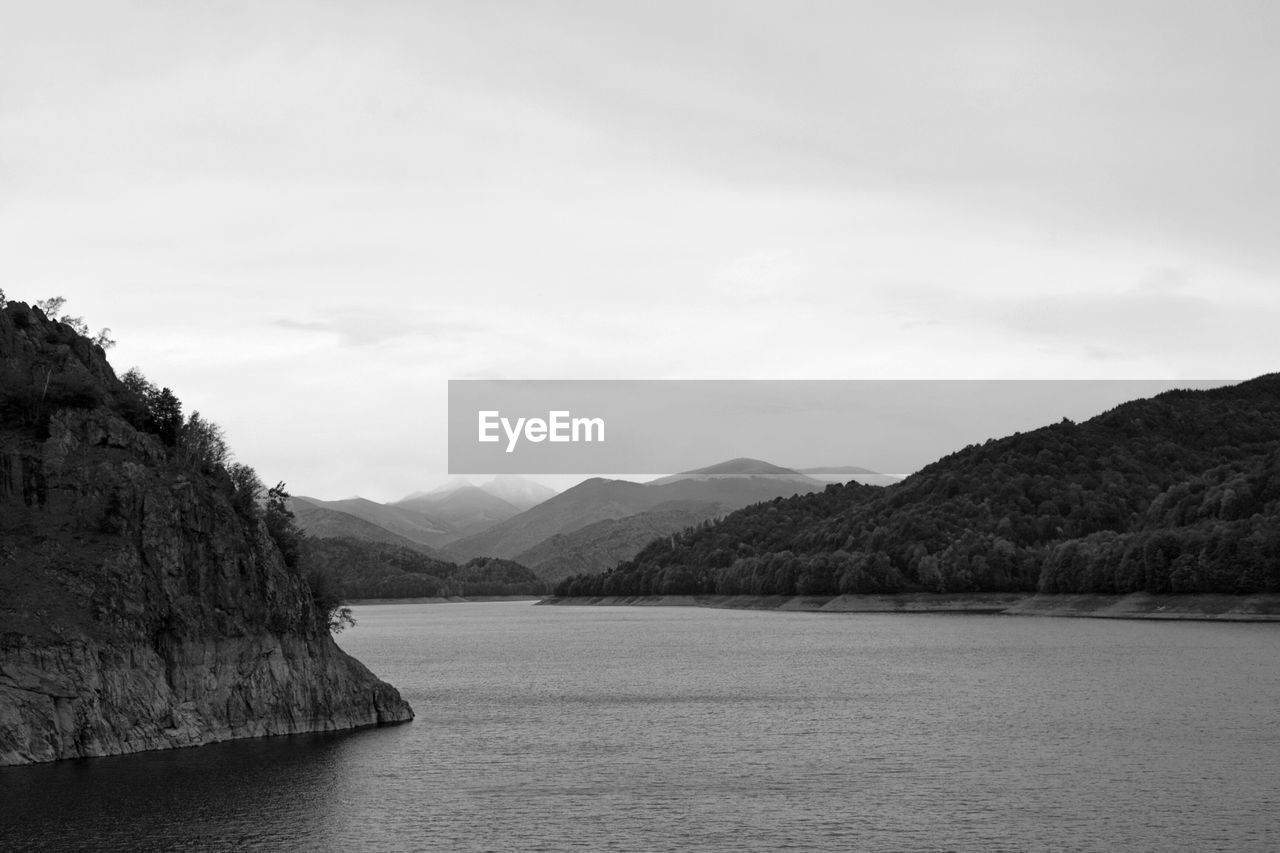 Scenic view of river by mountains against sky