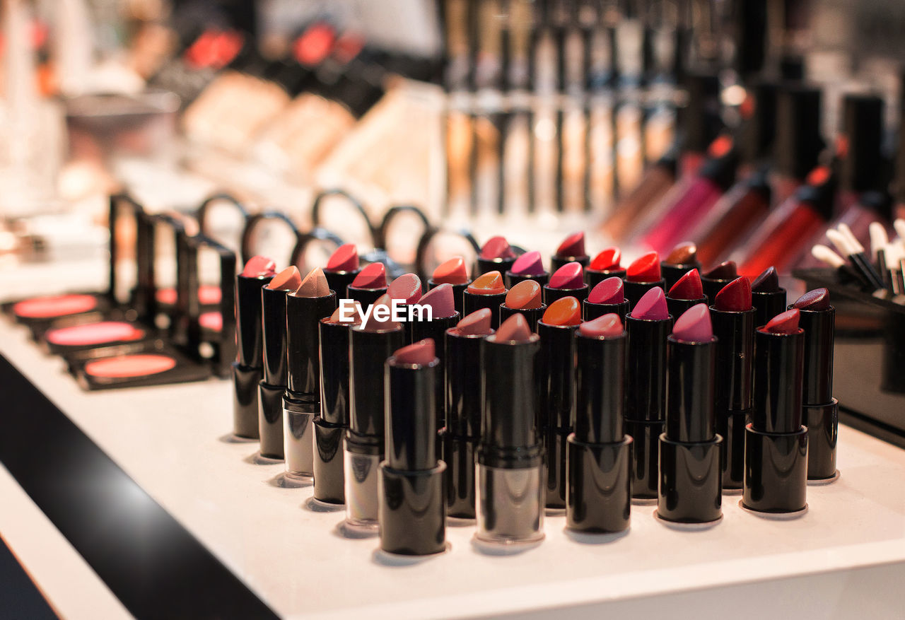 Different colors of lipstick and other cosmetics for makeup on the shop window in the cosmetic store