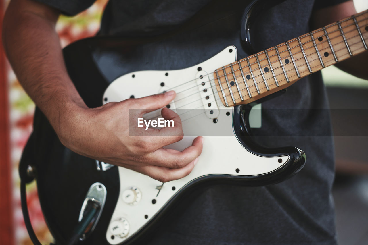 Midsection of man playing guitar