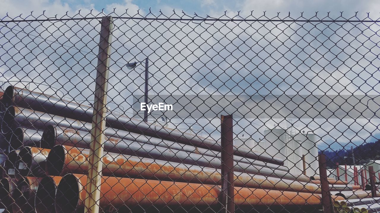 CHAINLINK FENCE AGAINST SKY SEEN THROUGH METAL RAILING