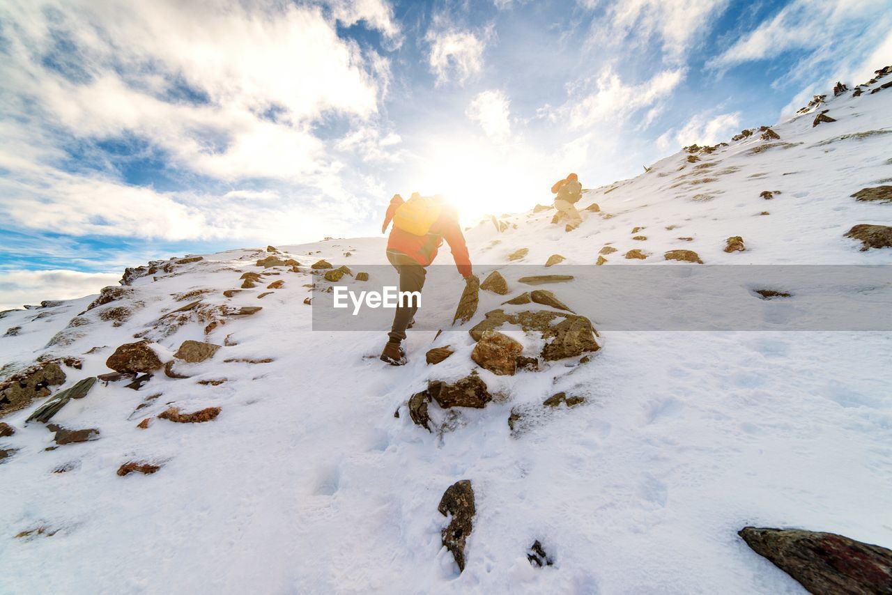 Low angle view of men climbing snowcapped mountain