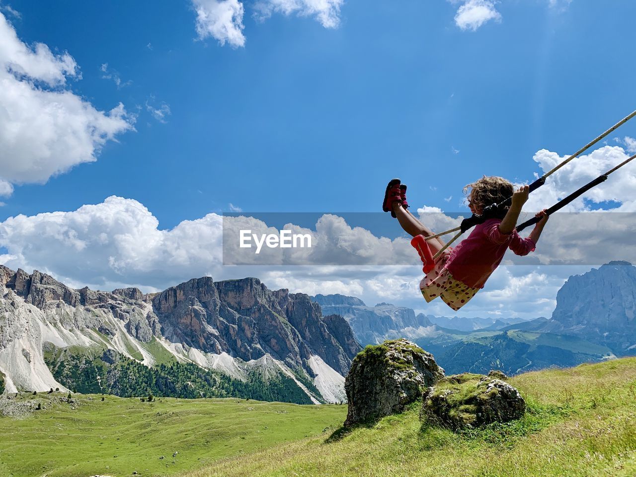 Girl on swing at mountain against sky