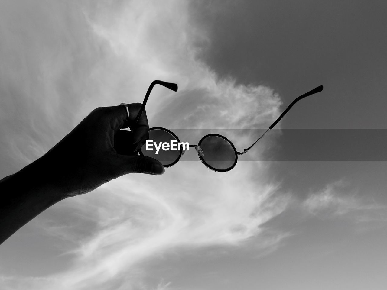 LOW ANGLE VIEW OF PERSON HOLDING SUNGLASSES AGAINST SKY