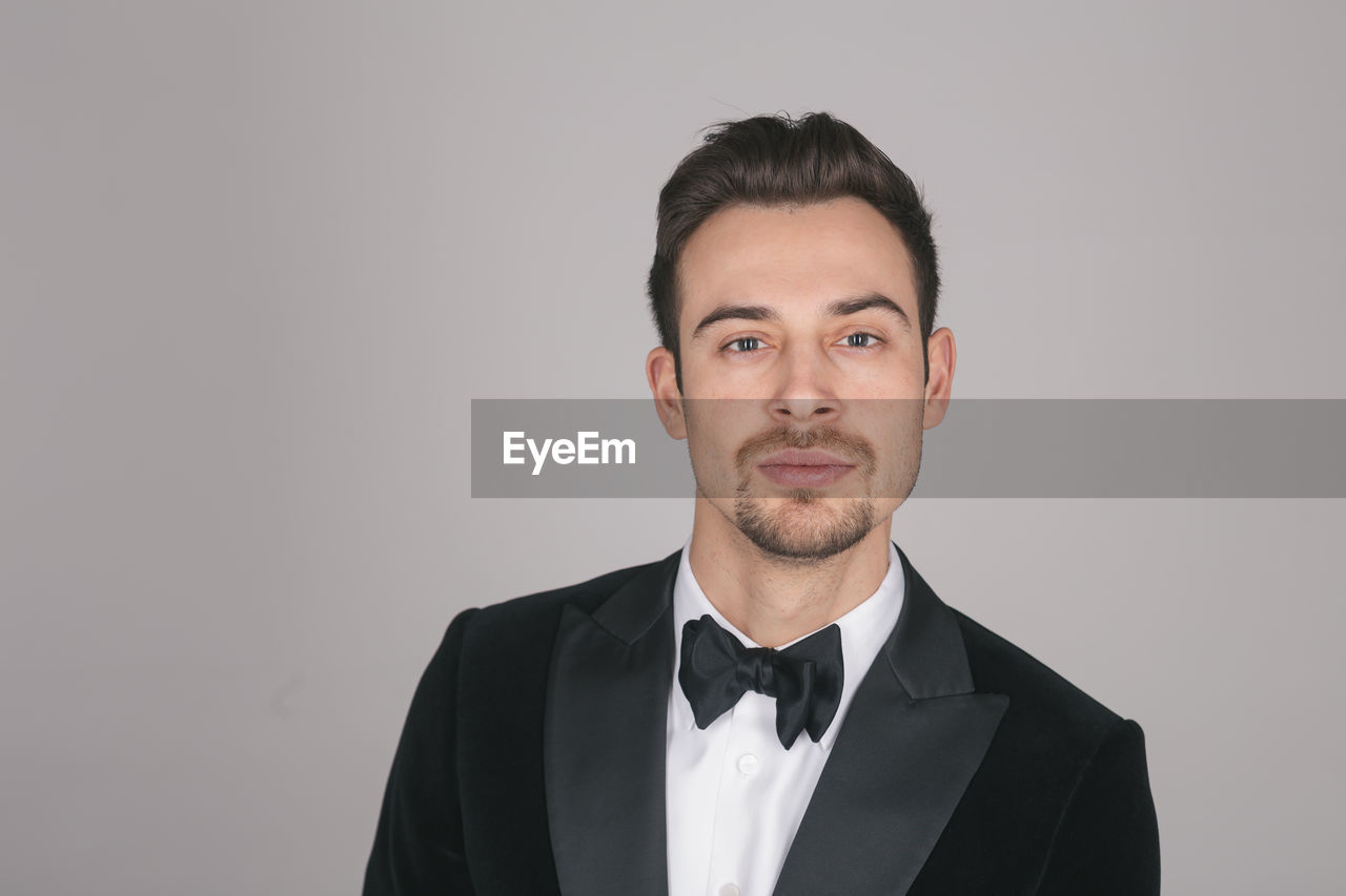 PORTRAIT OF YOUNG MAN AGAINST GRAY BACKGROUND