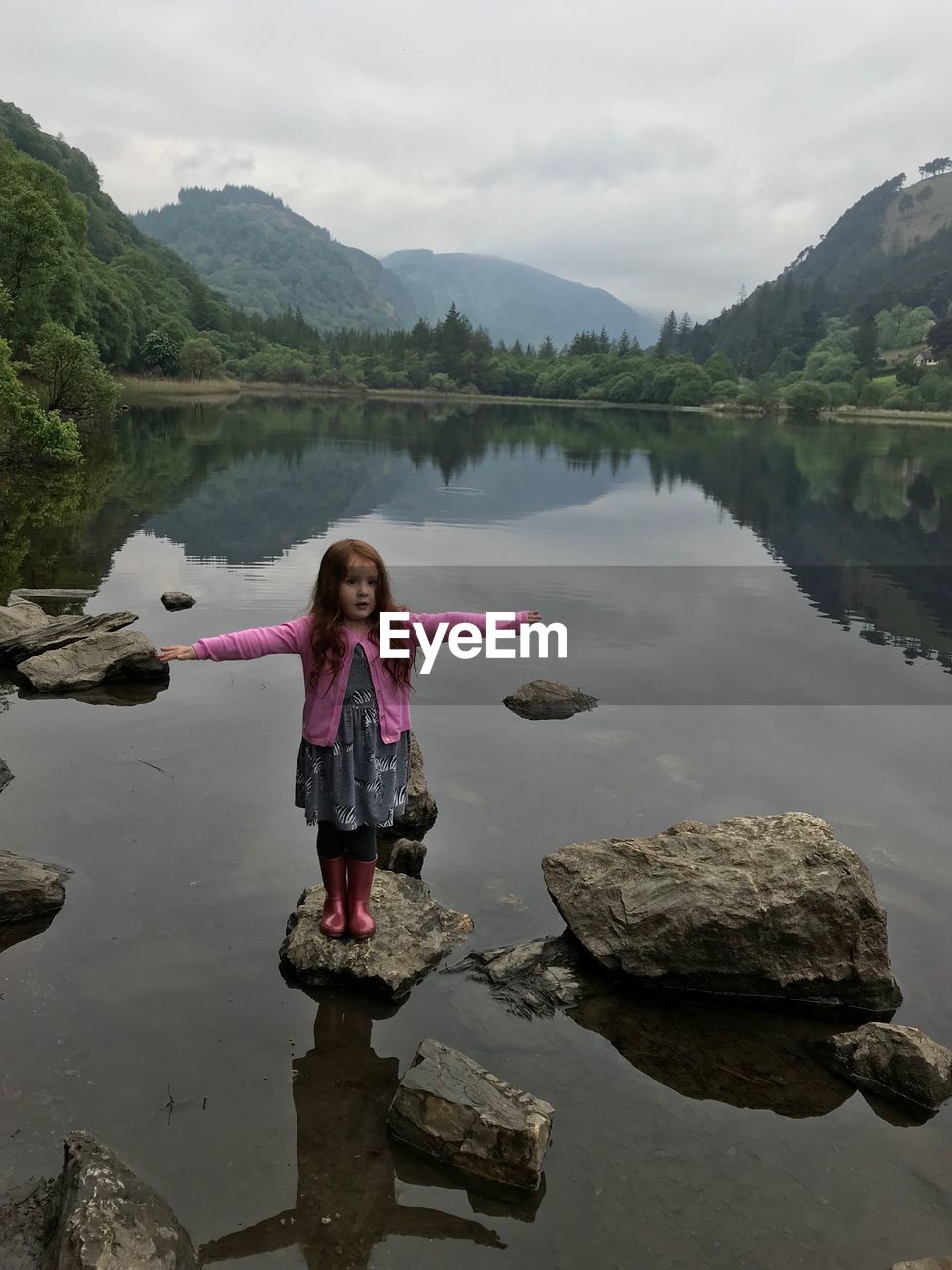 Girl standing on rock against lake