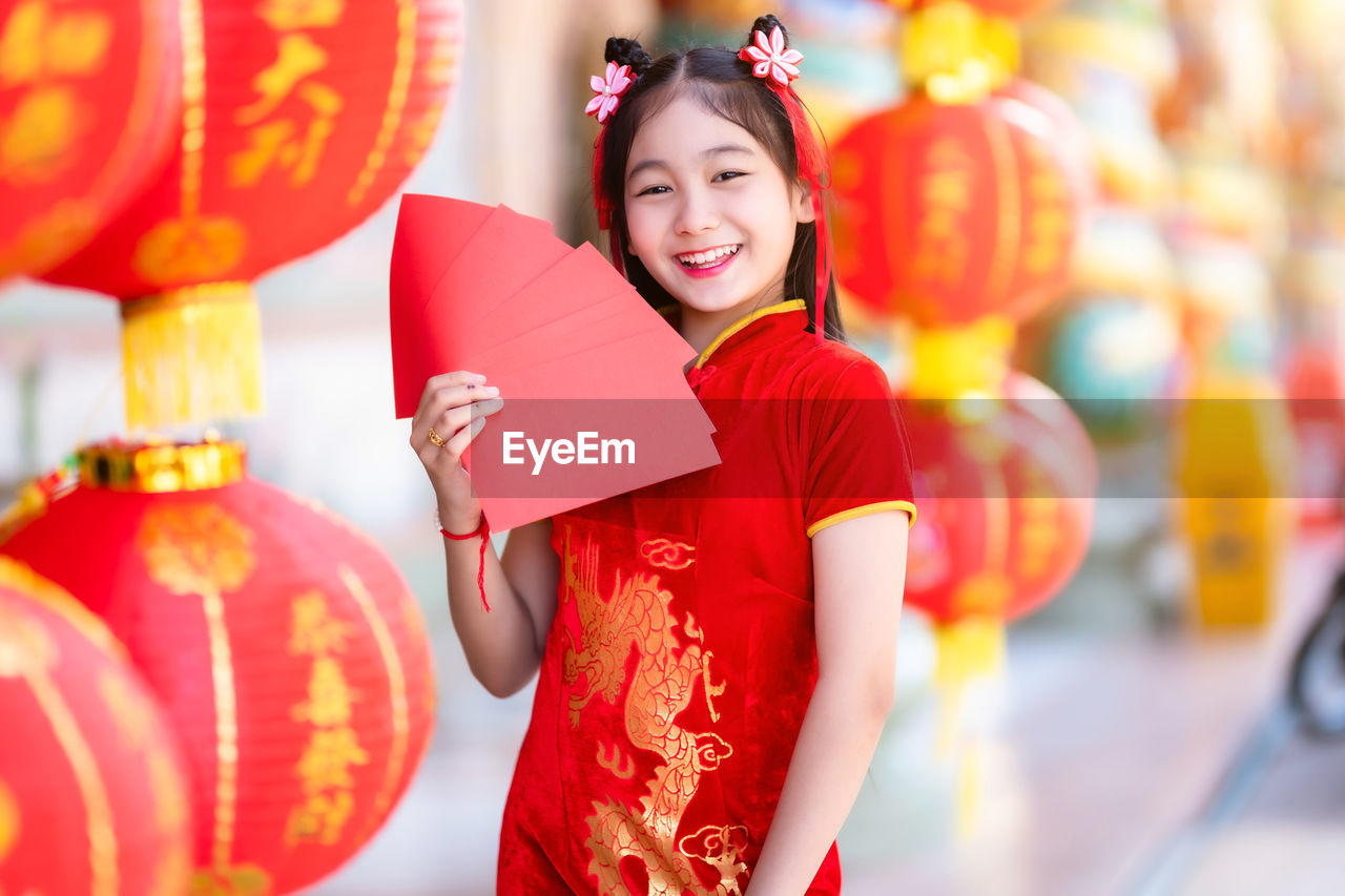 PORTRAIT OF A SMILING YOUNG WOMAN WITH RED UMBRELLA