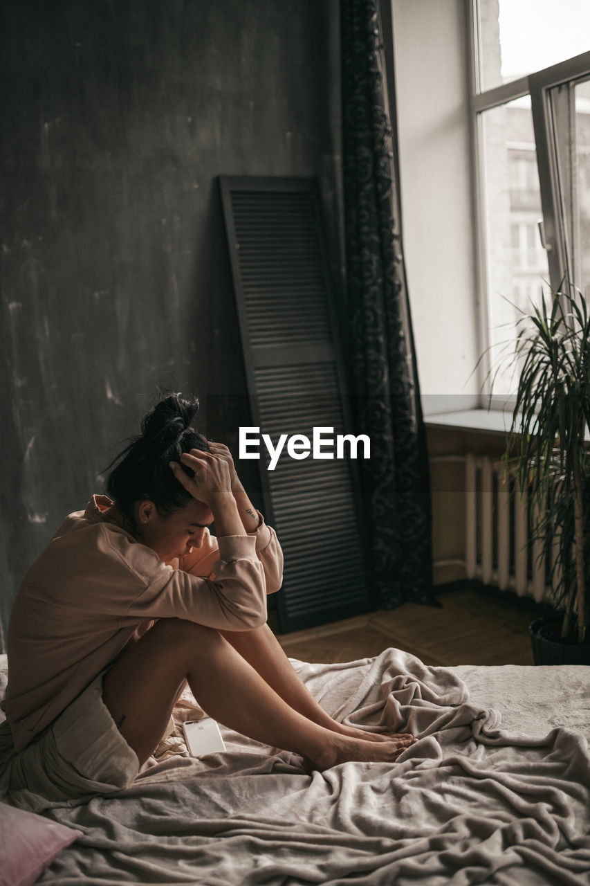 Woman sitting on bed at home