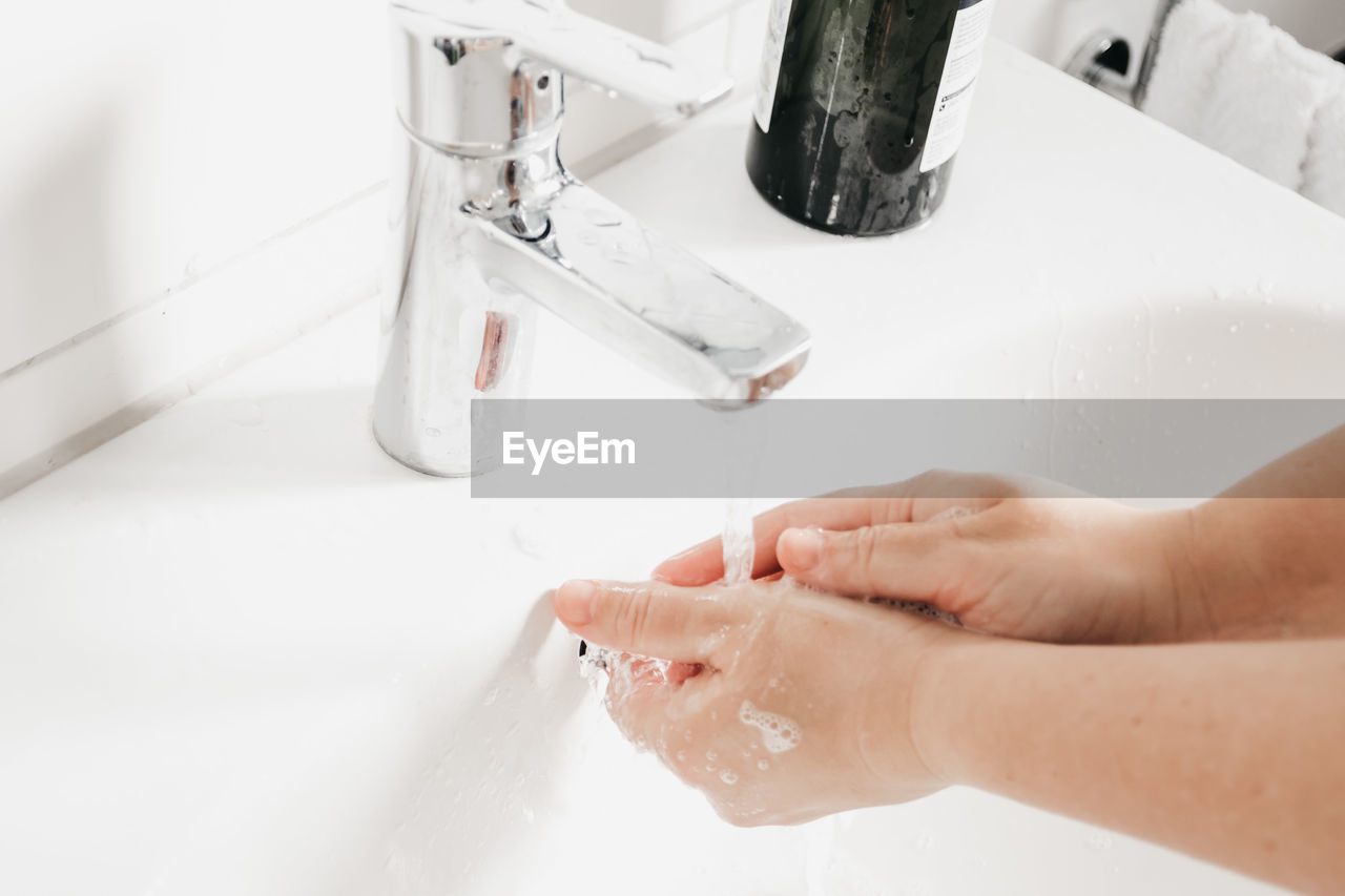 High angle view of woman washing hands in bathroom