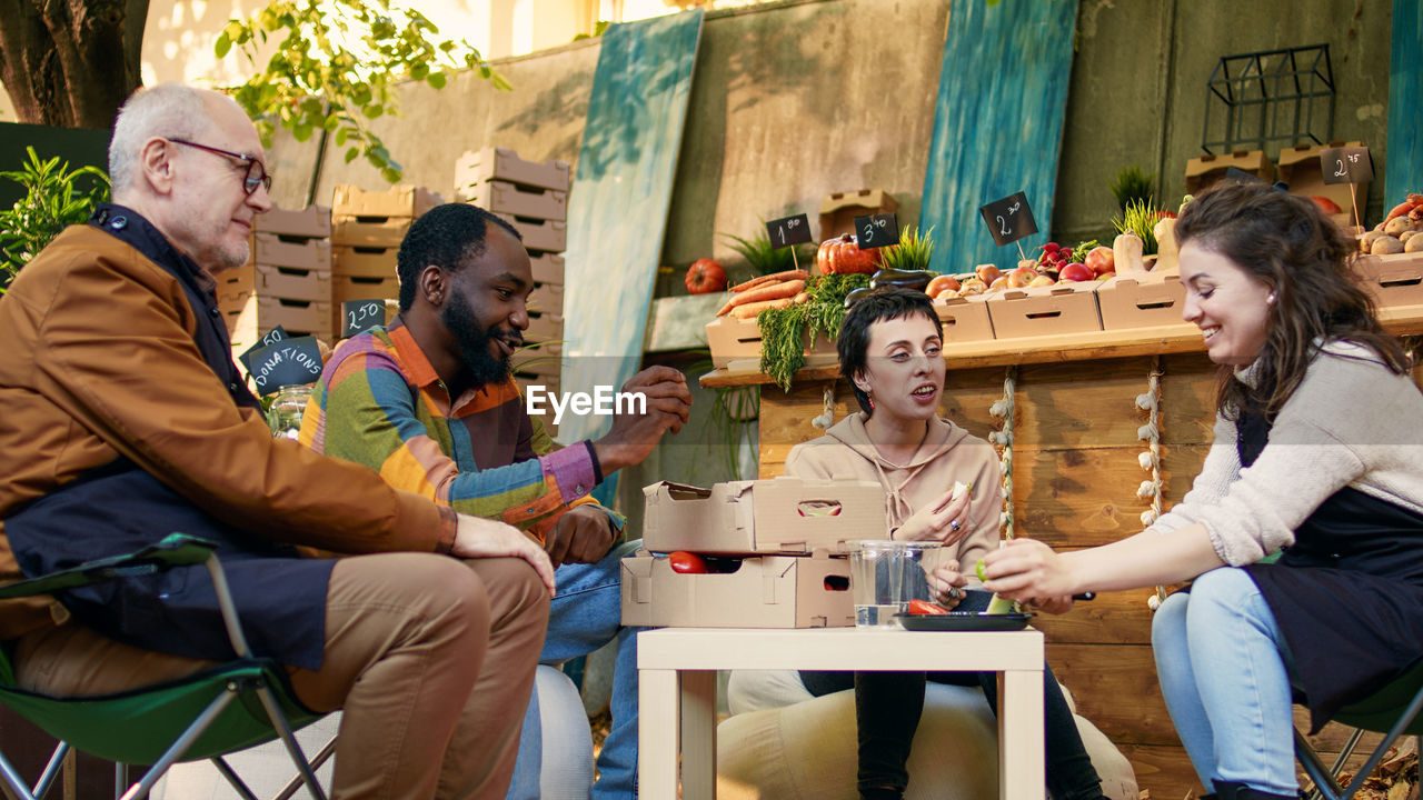 portrait of smiling friends using smart phone while sitting on table