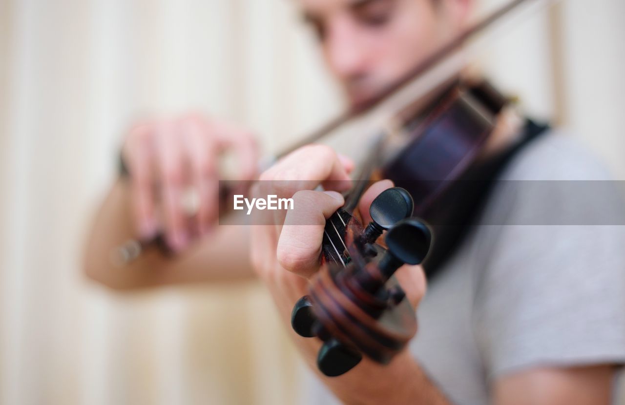 Close-up of young man playing violin at home