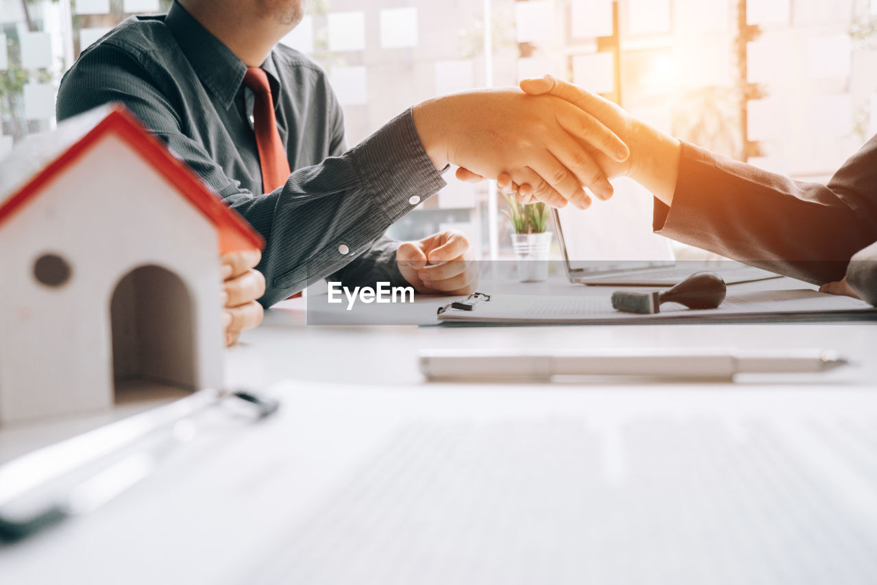 Business colleagues shaking hands at desk in office